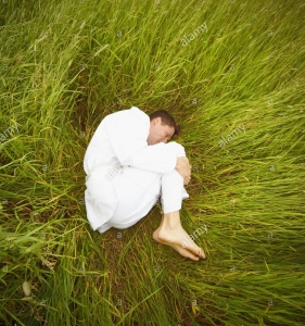 a-man-lying-in-the-grass-in-the-fetal-position-BRWA0P